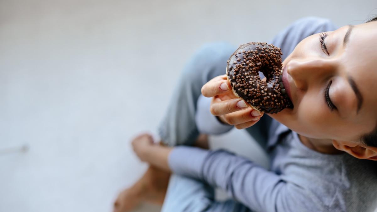 femeie care mananca o gogoasa